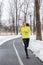 Winter runner girl training running in snow wearing cold weather clothes, gloves, warm yellow jacket. Asian woman