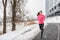 Winter running Asian girl wearing cold weather clothing for outside exercise in snow storm snowfall during winter training