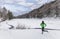 Winter running in mountain forest nature river with snowing weather. Woman runner trail running in snow in cold winter