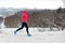 Winter running in park: happy active woman runner jogging in snow with Kyiv city skyline view, outdoor sport and fitness