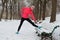 Winter running in park: happy woman runner warming up and exercising before jogging in snow