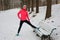 Winter running in park: happy woman runner warming up and exercising before jogging in snow, outdoor sport and fitness