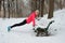 Winter running in park: happy woman runner warming up and exercising before jogging in snow, outdoor sport and fitness