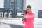 Winter running smartwatch fitness girl in cold snow weather jogging outside on street wearing smart watch and windproof clothes