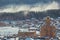 Winter rural landscape with a snowstorm in the Russian Urals with snow covered wooden houses