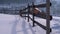 Winter Rural Scene with Old Abandoned Wooden Fence and Snowy Wooden House and Mountains