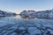Winter scene of boat in frozen fjord and snowy mountains
