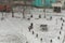 Winter scene on the yard from a bird`s eye view. An unidentified woman plays on the playground with children during a snowfall