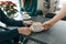 Winter season in the coffee shop. Closeup hand of man barista with cup of art coffee, table with sitting women, red Christmas