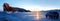 Winter Siberian landscape at sunrise. A car on ice and a rock on Lake Baikal. Banner format.