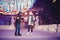 Winter skates, loving couple holding hands and rolling on rink. Illumination in background, night. Concept training