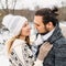 Winter snow couple love story.Beautiful girl in cozy hat and handsome bearded man hugs each other. pullover with