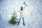 Winter snow decorating. Excited Woodcutter with axe in the winter forest. Bearded man is carrying Christmas tree in the