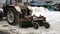 winter, a snow removal tractor removes snow from a city street