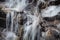 Winter snow runoff in motion against rocks and icicles