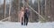 In the winter snowy forest, young men and women dressed in coats and scarves are walking and having fun. Loving couple