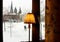 Winter square with snow view from window. Cozy interior with yellow lamp shade and curtains.