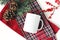 Winter still life. Blank coffee mug, fir tree branch, holly berries and pine cones. Checkered tartan plaid. Christmas