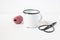 Winter still life composition with blank white metal coffee mug, vitage scissors and red decorative gift rope on white