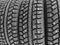Winter studded tire. Winter car tires background. Tire stack background. Tyre protector close up. Square powerful spikes. Black