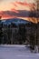 Winter sunset alpine top  view from mountain village and fir forest in front. Picturesque seasonal, nature and countryside beauty