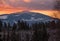 Winter sunset alpine top  view from mountain village and fir forest in front. Picturesque seasonal, nature and countryside beauty