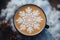 Winter themed latte coffee cup with snowflake art on foam, top view on blurred background