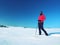 Winter tourist with snowshoes walk in snowy drift. Hiker in pink sports jacket