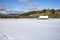 Winter view with covered by snow field and day cab semi truck with box trailer driving on the local road making cargo delivery