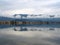 Winter view of Mesolonghi lagoon, Greece, mirroring sky and clouds, with solitary bird on pole