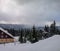 Winter view overlooking a lodge in the mountains surrounded by evergreens and snow on a cloudy day, in Ranca resort, Romania