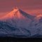 Winter volcanic landscape of Kamchatka Peninsula at purple-violet sunset: active volcano erupting