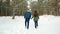 Winter walk, Beautiful guy and the girl go on a snowy road through the trees, the happy couple in love
