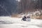 Winter walk with family on a snowmobile on a frozen river. A snowmobile with a trailer rolls children on the ice of the
