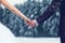 Winter wedding couple bride and groom holding hands over snowy forest background