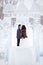 Winter wedding couple kissing in the middle of the ice figures in a snowy town, the bride in fur coat and white dress