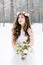 Winter wedding portrait. Portrait of beautiful bride with floral and cotton wreath on the head, holding bouquet, wearing