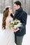 Winter wedding, stylish young couple, bride and groom, in the forest, tender hugs. Bride with long hair in cotton wreath