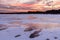 Winter, white snowdrifts, side view of a wooden house at sunset, pink sky, sunset.