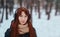 Winter. Woman with red hair wearing ear muffs looking at the camera.