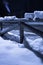 Wintertime fallen snow on wooden fence motif at night with smoke going out the chimney with back light