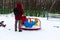 Wintertime. Mom watching little kid sliding the slide on the playground