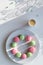 Wintertime sweets on white background, long shadows. Pink and mint green macaroons on white plate. Espresso cup, flat