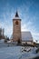 A wintertime view of a small church with a tall steeple