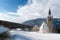 A wintertime view of a small church with a tall steeple