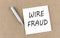 WIRE FRAUD text on sticky note on a cork board with pencil