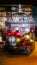 Wire and metal cage full of Christmas ornaments and lights against a dark blurry room background with shelves and laying next to b