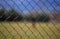 Wire metallic mesh fence around a soccer field. Blurred background, close up view with details.