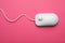Wired computer mouse on pink background