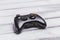 Wireless black gamepad or game controller for console gaming on white wood table